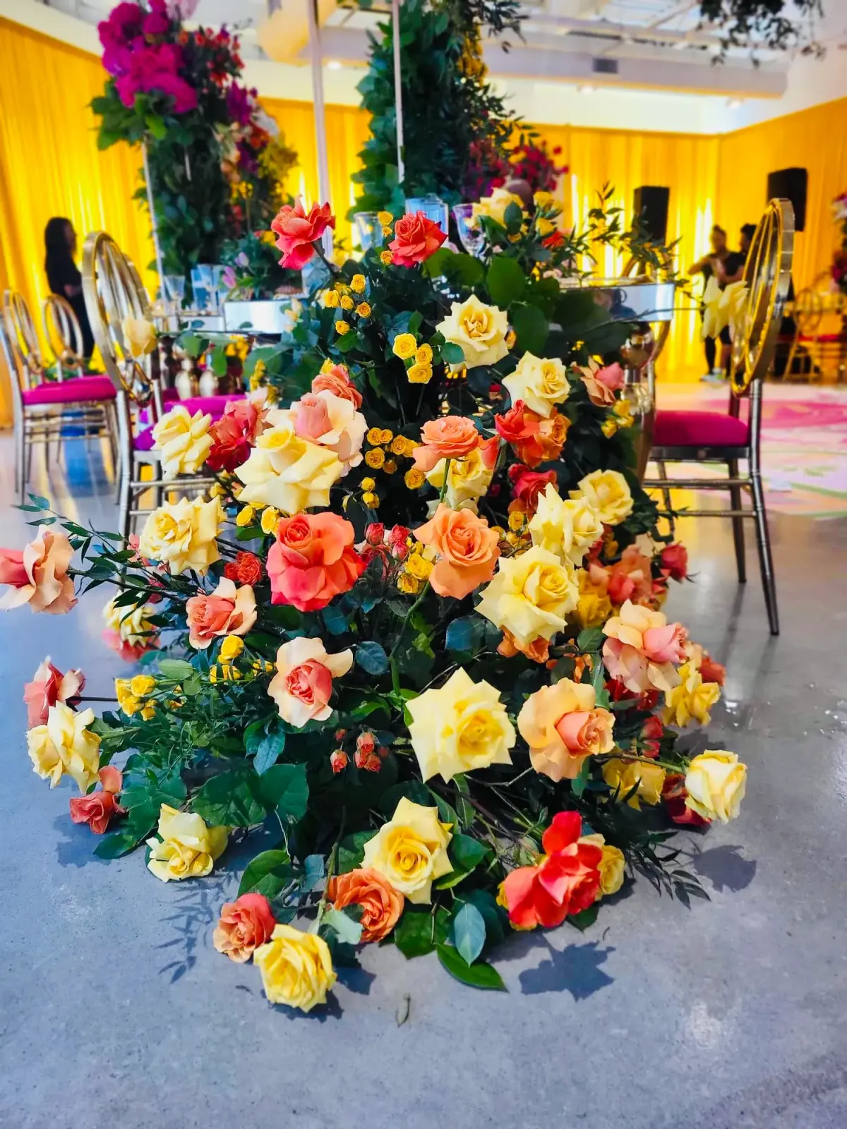 Oversized rose arrangement finished tableside in a colorful ballroom by Greystone